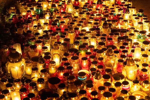 Colorful candle jars glowing warmly at cemetery on all saints day. A huge number of multicolored