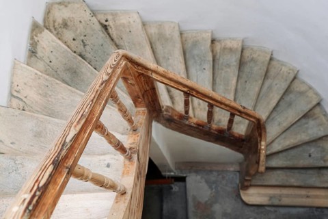 The steps of a wooden spiral staircase in an old building. An old wooden staircase in an old