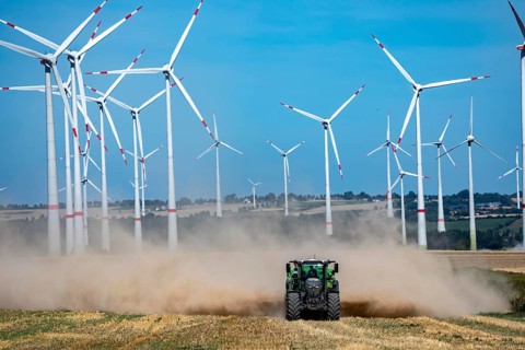 Tractor with mineral fertilizer spreader, cultivates a harvested grain field, spreads mineral