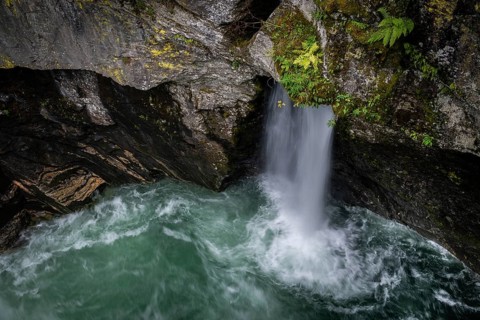 View of a small waterfall and a pool from the historic Øvstestølbrua stone arch bridge, long