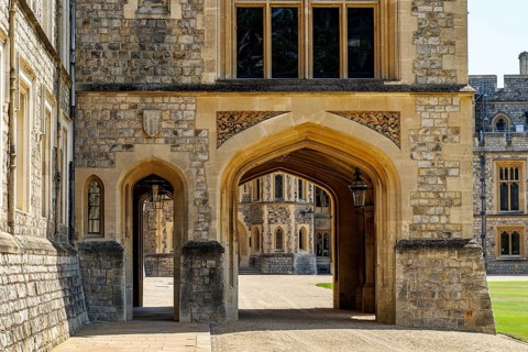 A carved stone archway framed by Gothic tracery opens into the Upper Ward of Windsor Castle,