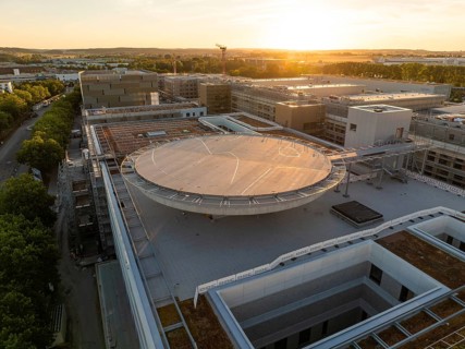 Round building under construction during sunset that bathes the urban landscape in warm light,