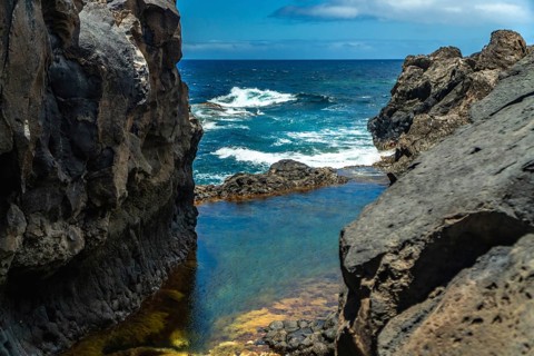 Volcanic rock formations creating a beautiful natural swimming pool with clear blue water,
