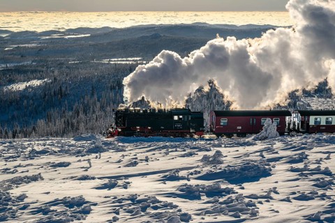The Brocken Railway with steam locomotive in atmospheric backlight on the way to the snow-covered
