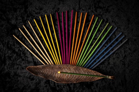 Colorful incense sticks and an incense holder arranged on a black background