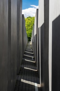 Light and shadow in the corridor of the memorial to the murdered Jews with a view of a green tree,