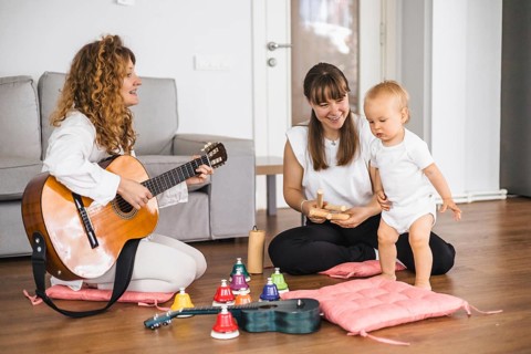 A relaxed setting where a toddler engages in a music activity with guitar and ukulele