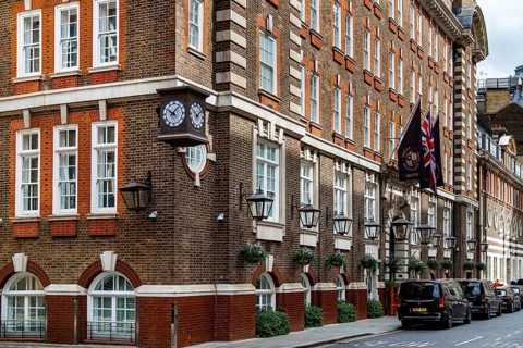 A projecting clock and a Union Jack flag mark the corner of the Great Scotland Yard Hotel, its red