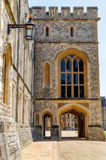 A crenellated gatehouse tower pierced by a large Gothic traceried window overlooks a smaller