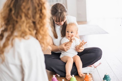 A mother and toddler engaging in a music activity with colorful bells on a bright day
