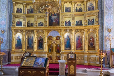 Rich orthodox iconostasis with gilded icons and candles in the center of a sacred space, Capriana
