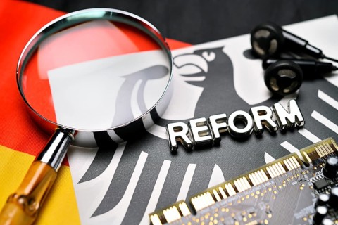 Reform lettering, magnifying glass and computer board on federal eagle and German flag, symbolic