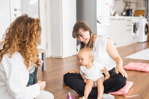 A woman interacting with a baby in a casual setting indoors, emphasizing bonding