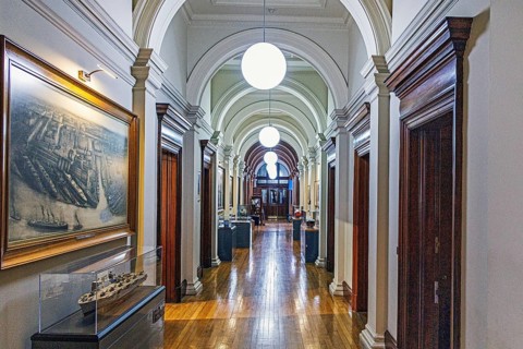 Vaulted corridor lined with arches, a ship painting and model display cases at the former Fairfield