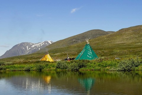 Sami tent droppings are reflected in a lake, on the left the Akka massif in Stora Sjöfallet N.P,