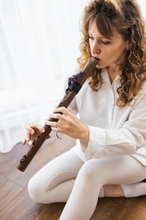 A woman with curly hair playing a flute, captured in a moment of focus