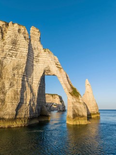 Aerial view of the Porte d'Aval rock formation shortly after sunrise, well-known landmark on the