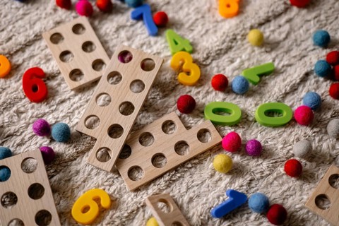 Wooden counting toys and scattered colorful balls on a textured surface
