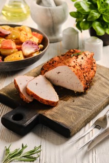 Roasted turkey breast on wooden cutting board. Slices of turkey meat are arranged next to whole
