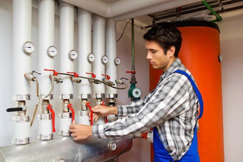 A young heating technician in a boiler room of a heating plant, heating, maintenance, Austria