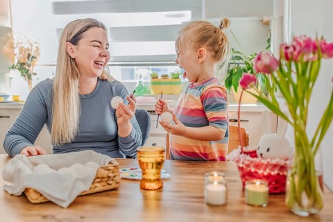 Mother and little daughter painting Easter eggs at home. family tradition, spring celebration and