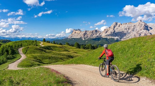 Woman cycling with electric mountain bike below the spectacular summits of Fanes Group, Dolomites,
