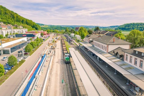 Railway station with adjacent construction and green landscape, construction site by Leonhard Weiss