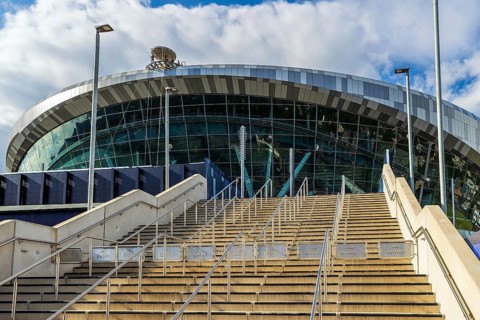 A wide stone stairway rises toward the glazed bowl of Tottenham Hotspur Stadium, London, England,