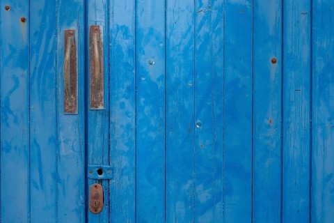 An old wooden door in strong blue with metal handles and visible patina, Majorca, Balearic Islands,