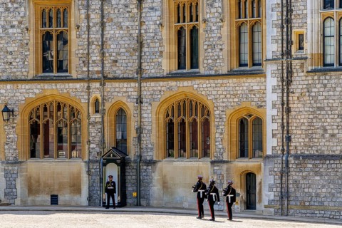 Soldiers in ceremonial uniform parade in front of Windsor Castle's State Apartments during the