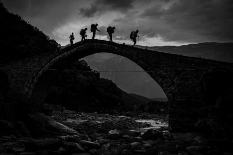 BENJA, ALBANIA - JULY 1, 2026: Black and white dramatic silhouette of hikers carrying backpacks
