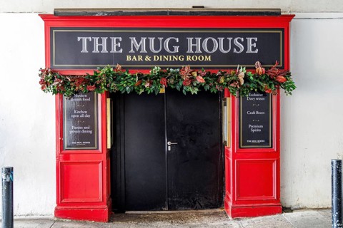 Floral garlands frame the dark doorway of The Mug House, a bar and dining room set beneath the