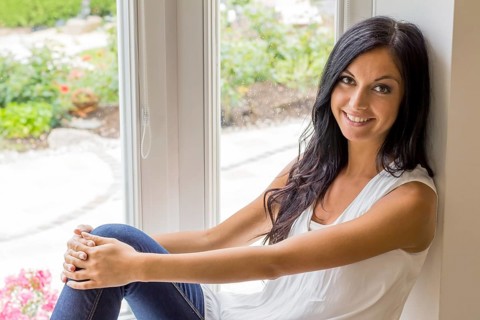 A young dark-haired woman sitting at the window and relaxing, studio shot, 25 years