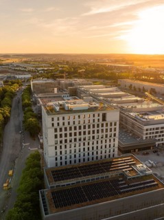 Modern high-rise building with adjacent street and surrounding urban infrastructure at sunset,