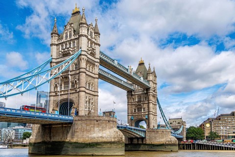 Viewed from the Thames footpath, the Gothic stone turrets of Tower Bridge frame its pale blue