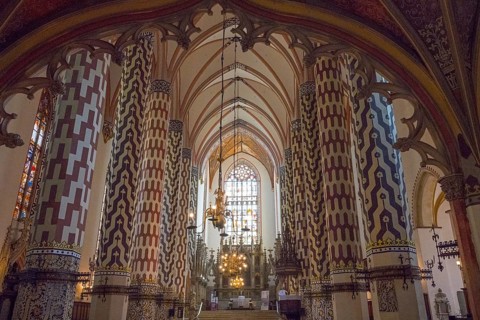 Magnificent Gothic church interior with decorated columns and colorful glass windows illuminated by