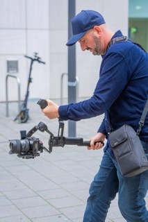 Man operates a camera with gimbal outdoors in front of a building, Milaneo, Stuttgart, Germany