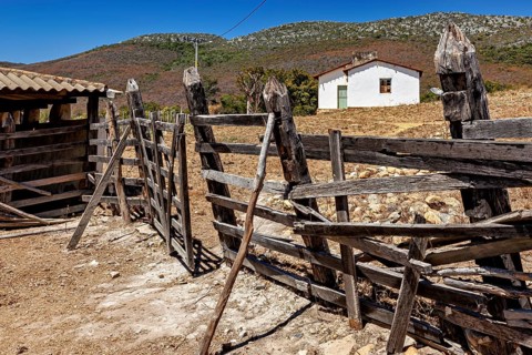 A rustic wooden fence leads to a hut in a mountainous, rural area, settlement and villages in the