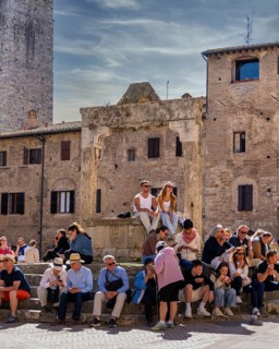 Tourists around the market square with old fountain and other sights in San Gimignano, Tuscany,