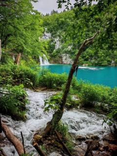 A lively waterfall surrounded by green vegetation and blue waterfall, Plitvice Lakes National Park,