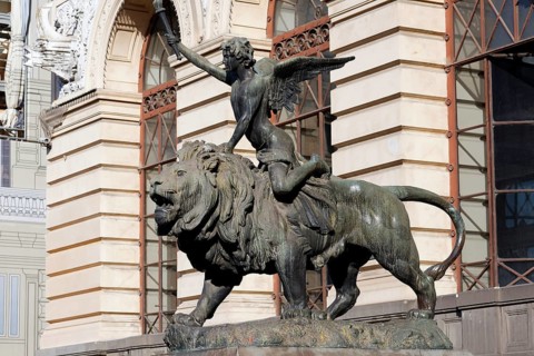 Winged boy riding on a lion, allegorical bronze sculpture in front of the Palazzo della Borsa,