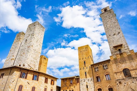 Towers of the old Town with historic buildings from Piazza del Duomo at San Gimignano on a sunny