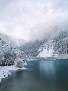 Low clouds over the turquoise water of the mountain lake in winter. Winter landscape, A serene