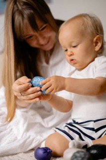 Mother and baby engaging with a blue toy, sharing a moment