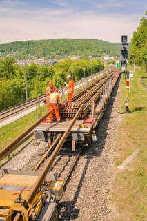 Workers in orange on rail cars working on the tracks next to signals, Leonhard Weiss construction