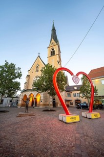 Illuminated St. Nicholas Church and bronze figure of Francis of Assisi, blue hour, heart at Paul