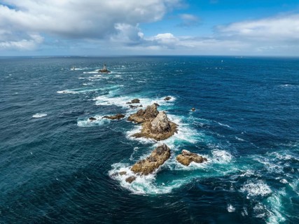 Aerial view of the wild foaming sea at Pointe du Raz with the offshore Phare de la Vieille