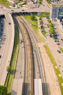 Aerial view of a municipal train station with tracks, roads and parked cars, construction site by