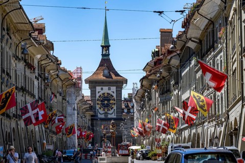 Kramgasse with historic houses decorated with cantonal flags and Swiss national flags, back clock