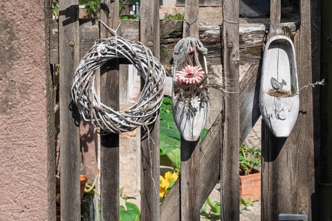 A rustic wooden fence with decorative wreath and floral decoration in a vintage atmosphere, Alsace,